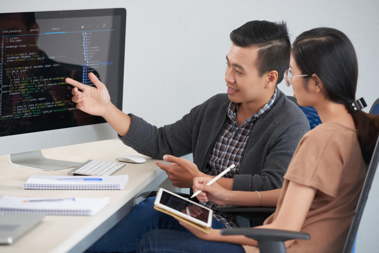 Cheerful programmer showing code to his female coworker or teacher